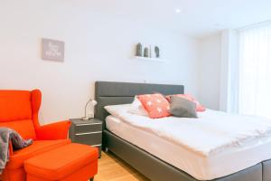 1 dormitorio con 1 cama y 1 silla naranja en Meric Apartment, en Zermatt