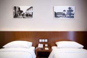 PRIME PARK Hotel Bandung في باندونغ: سريرين في غرفة فندق مع صورتين على الحائط
