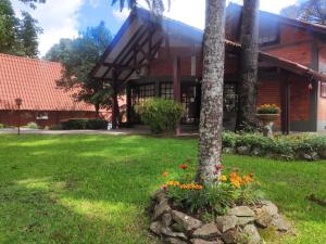 a building with a tree and flowers in a yard at Hotel Cabana Jardim de Flores in Gramado