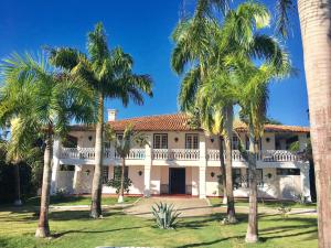 a large white house with palm trees in front of it at Casa Grande São Vicente in Arraial d'Ajuda