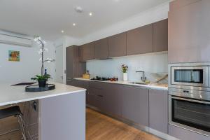 a kitchen with brown cabinets and a white counter top at Bermondsey Central London Apartments in London +30 photos
