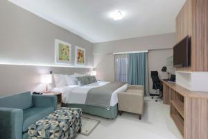 a hotel room with a bed and a chair and a tv at Comfort Hotel Fortaleza in Fortaleza