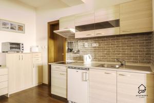 a kitchen with white cabinets and a brick wall at TATRYSTAY Apartment C3 in Veľká Lomnica