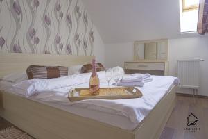 a bottle of wine on a tray on a bed at TATRYSTAY Apartment C3 in Veľká Lomnica +5 photos