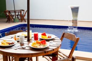 - une table avec des assiettes de nourriture à côté de la piscine dans l'établissement Pousada Arco Iris Fortaleza, à Fortaleza