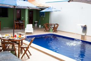 een zwembad met een tafel en stoelen en een parasol bij Pousada Arco Iris Fortaleza in Fortaleza