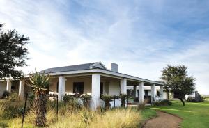 a white house with a palm tree in front of it at Elephant House in Addo
