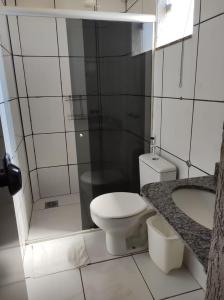 a white bathroom with a toilet and a shower at Hotel Boa Viagem in Barra do Garças