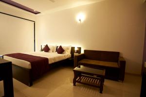 a bedroom with a bed and a couch and a chair at HOTEL CITY POINT in Shirdi