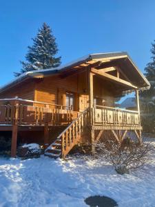 Cabaña de madera en la nieve con porche y escaleras en Chalet des Moineaux, en Saint-Laurent-du-Jura