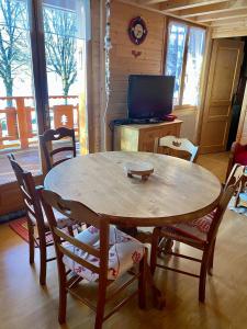 una mesa de madera y sillas en una habitación con TV en Chalet des Moineaux, en Saint-Laurent-du-Jura