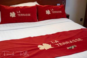 
a bed with a red and white blanket and pillows at Hotel La Terrasse in De Panne
