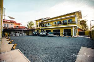 un estacionamiento con autos estacionados frente a un edificio en ApartPousada Residencial dos Reis, en São Francisco do Sul