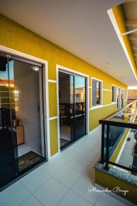 un couloir d'un bâtiment avec des murs jaunes et des portes en verre dans l'établissement ApartPousada Residencial dos Reis, à São Francisco do Sul