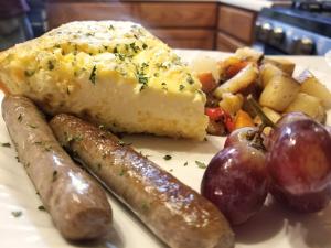 une assiette de nourriture avec des saucisses, des pommes de terre et d’autres denrées alimentaires dans l'établissement 5 Ojo Inn Bed and Breakfast, à Eureka Springs