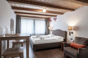 a bedroom with a bed and a desk and a chair at Stay COOPER l Goethe Guesthouse in Bolzano