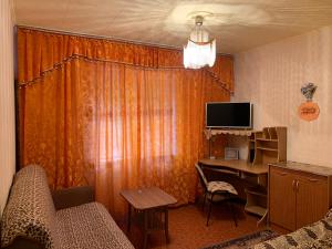 ナホトカにあるKvartira na Makarovaのデスク、テーブル、テレビが備わる客室です。