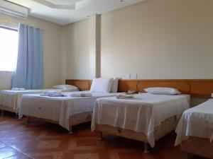 Cette chambre comprend 2 lits avec du linge de maison blanc. dans l'établissement Hotel Litoral, à Aracaju