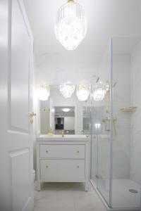 a white bathroom with a shower and a chandelier at Hamptons Apartment in Świnoujście