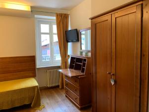 a bedroom with a bed and a dresser and a window at Hotel Serena Cortina in Cortina dʼAmpezzo