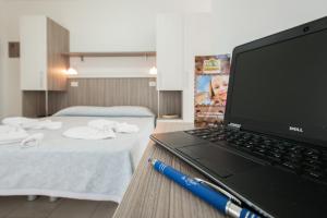 un computer portatile seduto su un tavolo accanto alla camera da letto di La Plata Hotel - con piscina a Riccione