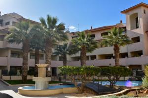 a hotel with palm trees in front of a building at Queens Gardens - Kato Paphos - next to Kings Ave Mall --- by Yiota in Paphos