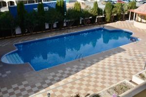 a large blue swimming pool on a tiled floor at Queens Gardens - Kato Paphos - next to Kings Ave Mall --- by Yiota in Paphos