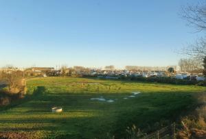 a large grass field with a river in the background at B&B HOTEL Ouistreham in Ouistreham