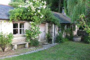 una pequeña casa de piedra con un banco en el patio en The Cartshed, en Osmington