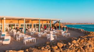 a restaurant on the beach with white tables and chairs at Westpoint Dakhla in Dakhla