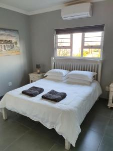 a bedroom with a white bed with two towels on it at Volgenoeg Self Catering in Oudtshoorn