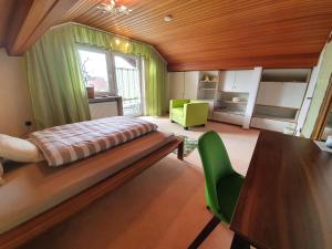a bedroom with a bed and a table and a green chair at Gästehaus Aurelia in Wiesau