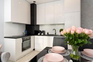 a kitchen with white cabinets and a vase of pink roses at Angel Apartments 2 in Krakow