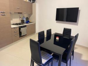 einen schwarzen Esstisch mit Stühlen und einen Flachbild-TV in der Unterkunft St Orsola Apartment 2 in Victoria