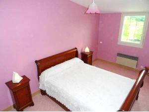 1 dormitorio con paredes moradas y 1 cama con 2 mesas en Maison de 2 chambres avec jardin clos a Saint Laurent la Roche en Saint-Laurent-la-Roche