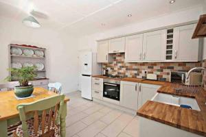 a kitchen with white cabinets and a wooden table and a table sidx sidx at Charming 2-Bed Cottage in the heart of Stanhope in Bishop Auckland