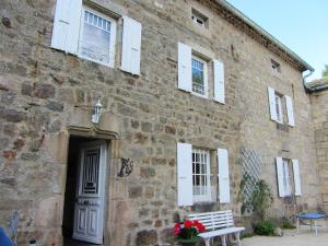 ein Backsteingebäude mit weißen Fenstern und einer Bank in der Unterkunft Maison de 4 chambres avec jardin amenage et wifi a Saint Andre en Vivarais in Saint-André-en-Vivarais