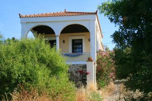 a small white house with a gate and bushes at 5 bedrooms villa at Limnos 250 m away from the beach with sea view enclosed garden and wifi in Lemnos
