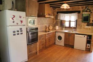 a kitchen with a white refrigerator and a dishwasher at Charming House in La Cavada with Jacuzzi in La Cavada