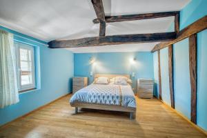 a blue bedroom with a bed and a wooden floor at Villa charmante en pleine campagne de Courrensan avec piscine privée in Courrensan