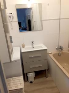 een badkamer met een wastafel, een bad en een spiegel bij Charmant appartement à Cavalaire-sur-Mer avec terrasse in Cavalaire-sur-Mer