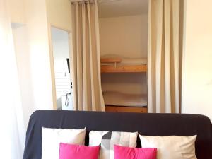 een slaapkamer met een bed met roze en witte kussens bij Charmant appartement à Cavalaire-sur-Mer avec terrasse in Cavalaire-sur-Mer