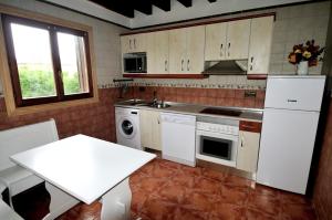 a kitchen with white appliances and a white table at Charming house in Albuerne with fenced garden in Albuerne