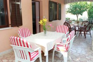 uma mesa branca e cadeiras com um vaso de flores em Apartment Bareta em Trogir