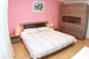 um quarto com uma grande cama branca com paredes cor-de-rosa em Apartment Bareta em Trogir
