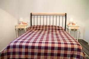 a bed with a plaid blanket and two night stands at Charming Villa in Benamahoma + Pool in Benamahoma +23 photos