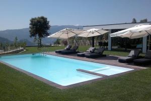 a large swimming pool with chairs and umbrellas at Elegant Villa Near Vieira do Minho with Pool in Vieira do Minho