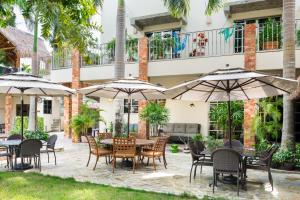 an outdoor patio with tables and chairs and umbrellas at Álamos Inn Hotel con Jacuzzi y Piscina in Cancún