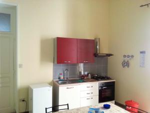 eine kleine Küche mit roten Schränken und einem Herd in der Unterkunft 2 bedrooms appartement with balcony and wifi at Marsala 4 km away from the beach in Marsala