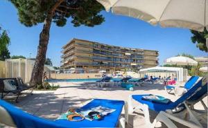 une piscine avec des chaises et des parasols et un bâtiment dans l'établissement Studio a Saint Laurent du Var a 100 m de la plage avec piscine partagee jardin clos et wifi, à Saint-Laurent-du-Var